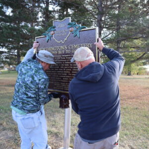 Two men lifting the Worthington Cemetery Ohio Historic Marker onto its post