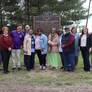 A group of people is gathered around the historic marker at Worthington Cemetery on the day of its dedication.