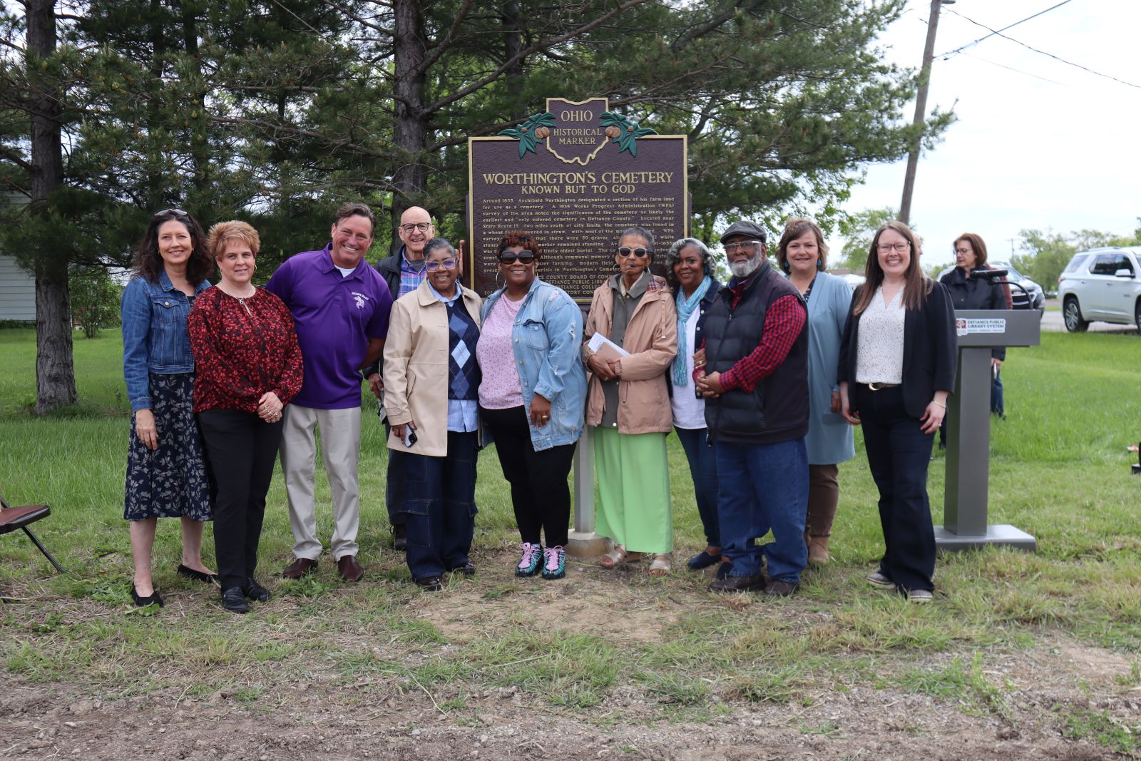 A group of people is gathered around the historic marker at Worthington Cemetery on the day of its dedication.